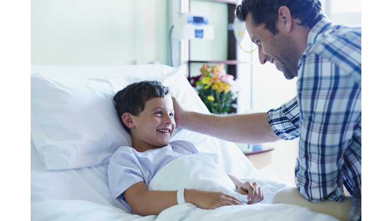 Loving father with ill son in hospital ward