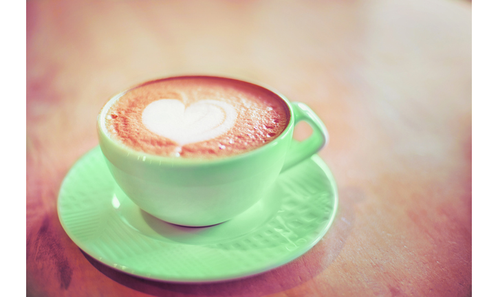 Mint cappuccino cup with with latte art heart on wood table