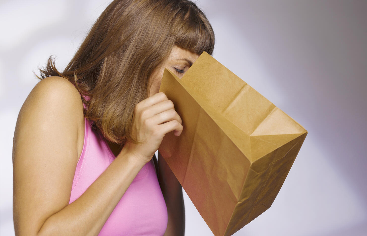 woman vomiting into paperbag