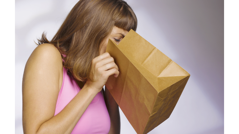 woman vomiting into paperbag