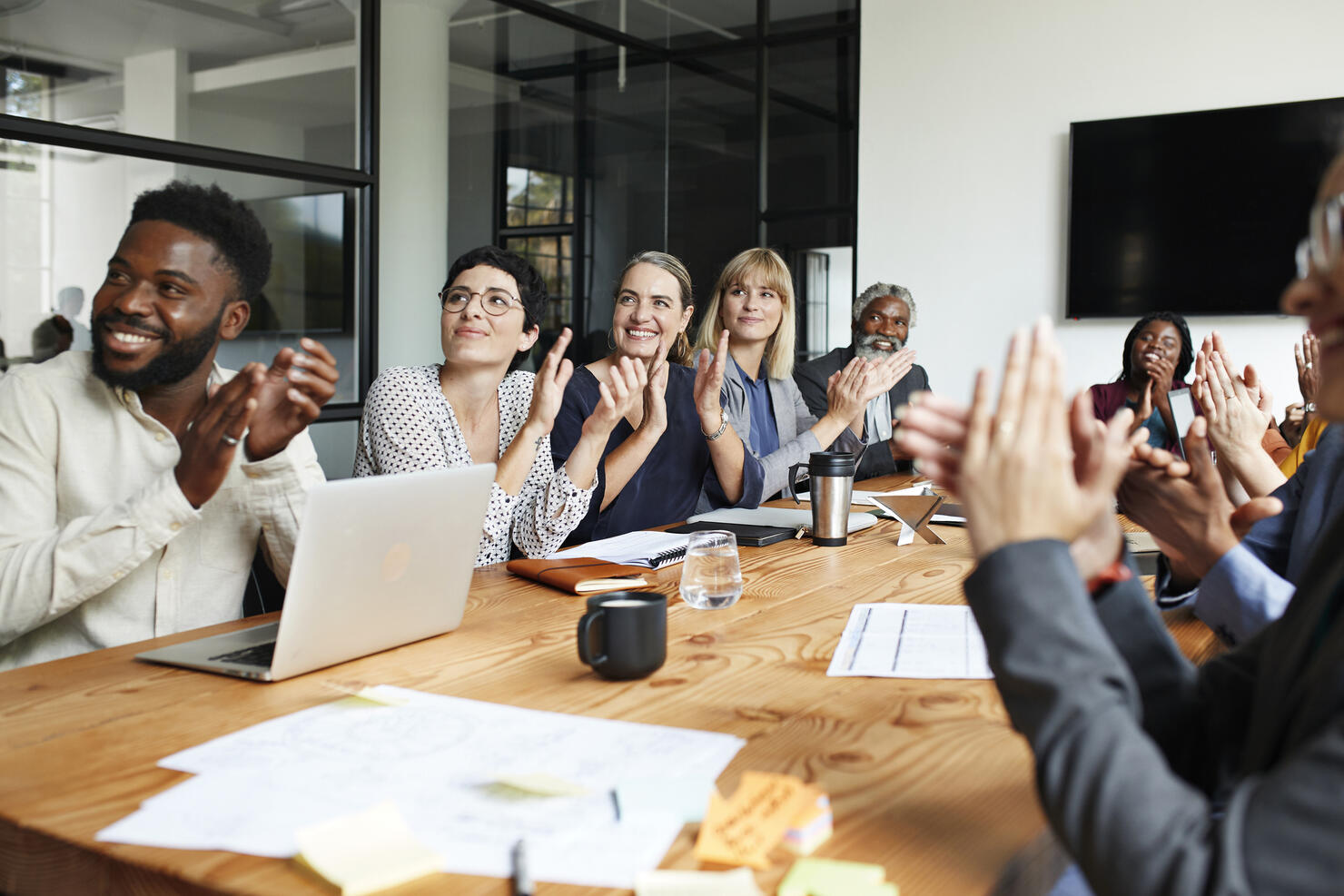 Executives clapping by table in office meeting