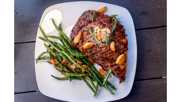 Charcoal Grilled Ribeye Steak Medium Rare Plated With A Side Of Sauteed Green Beans With Bacon And Garlic