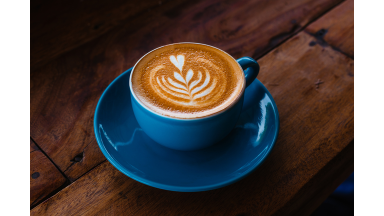 Cappuccino in a blue ceramic mug on a wooden table side view