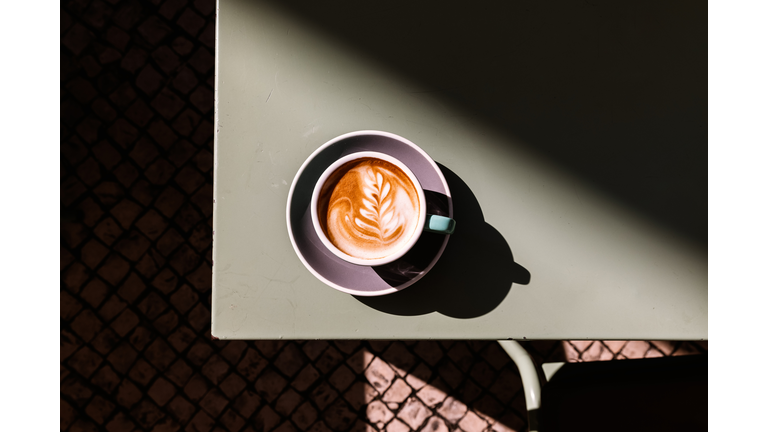 Cup of cappuccino with latte art on the table, directly above view