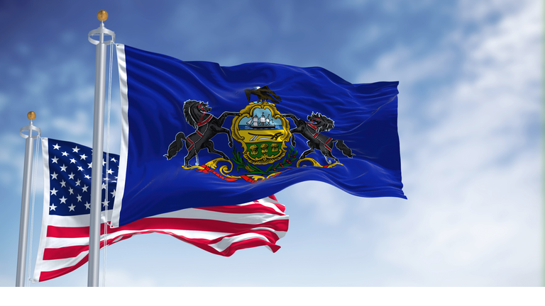 The Pennsylvania state flag waving along with the national flag of the United States of America
