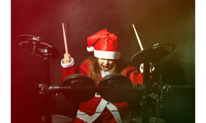 Little drummer disguised as Santa Claus playing the electronic drum kit