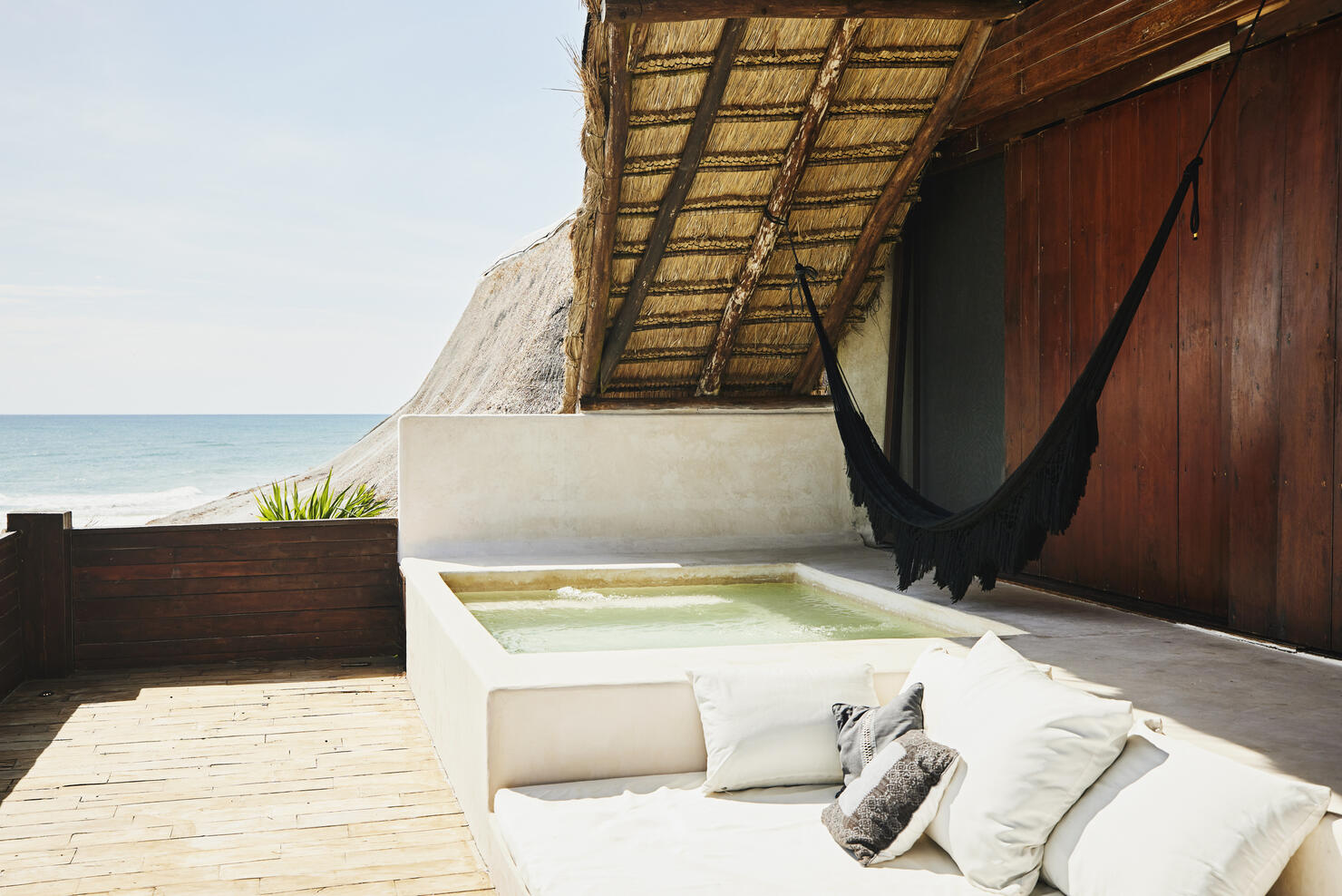 Wide shot of plunge pool on deck of luxury tropical villa overlooking ocean