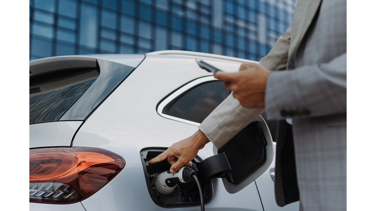 Close-up of businessman charging his car.