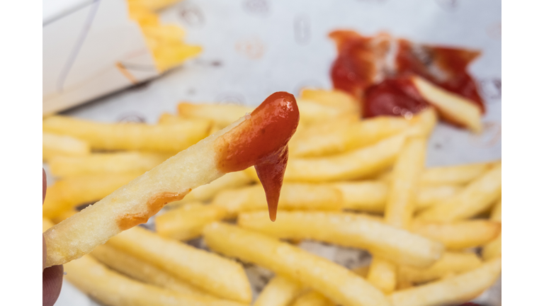 A person eating french fries with ketchup.