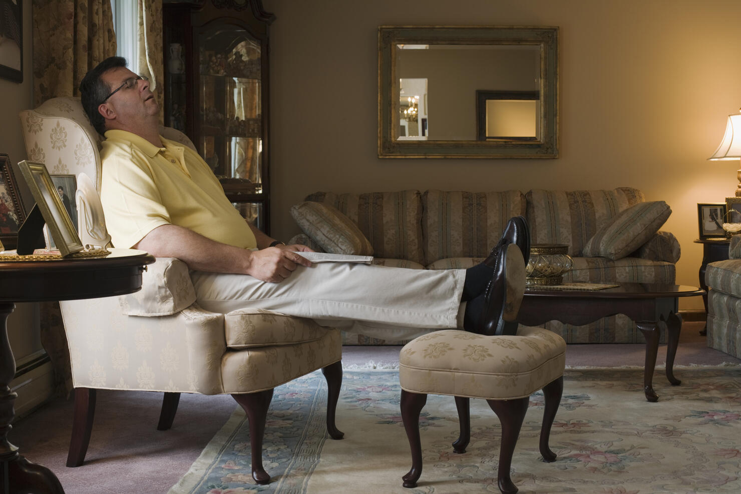 Mature man sleeping in armchair in living room, side view