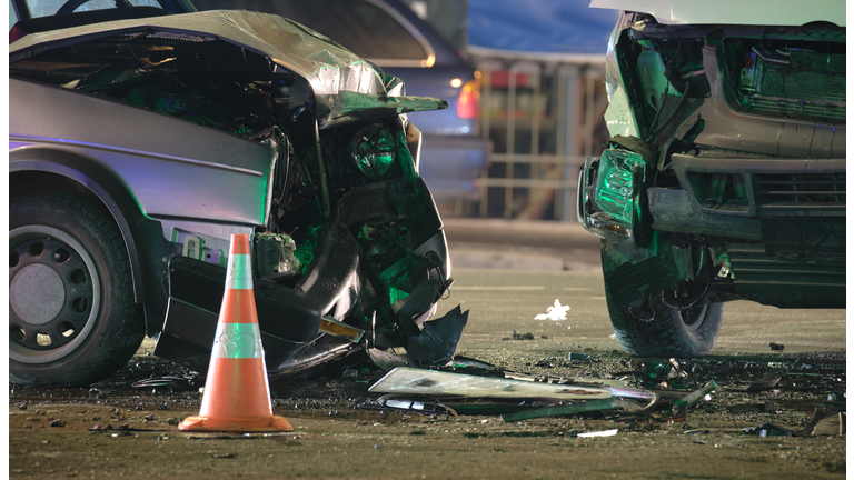 Damaged in heavy car accident vehicles after collision on city street crash site at night. Road safety and insurance concept