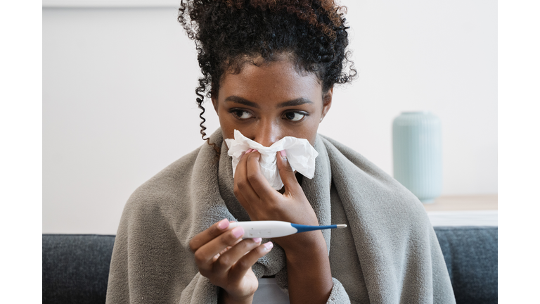 Black girl having flu, feeling bad and lying on the sofa