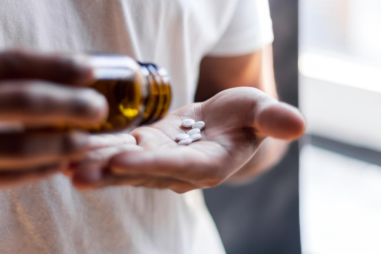 Young man spilling multiple pills in his hand.