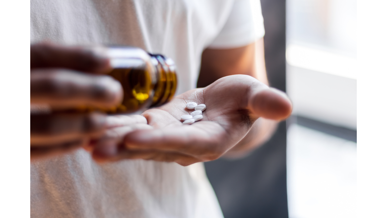 Young man spilling multiple pills in his hand.