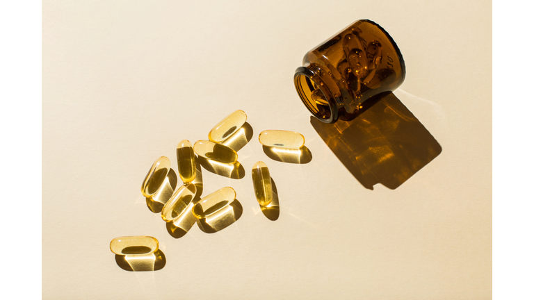 Omega 3 fish oil capsules and a glass bottle on a beige background.