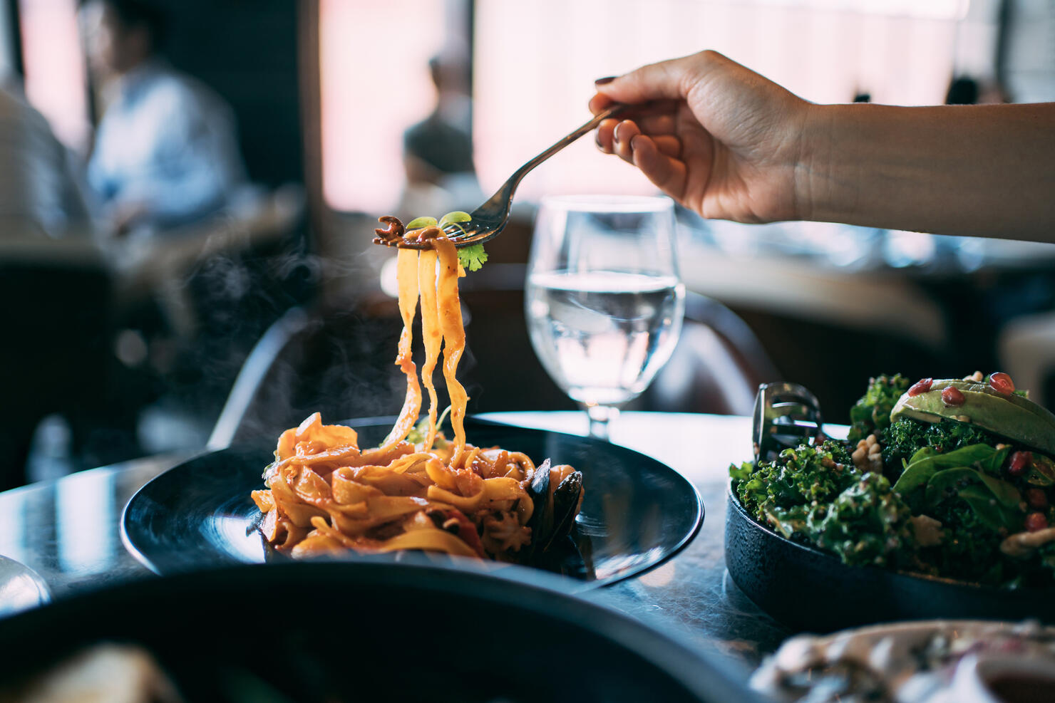 Close up of a woman eating seafood pasta. Sitting in dining table enjoying scrumptious meal in a restaurant. Eating out lifestyle