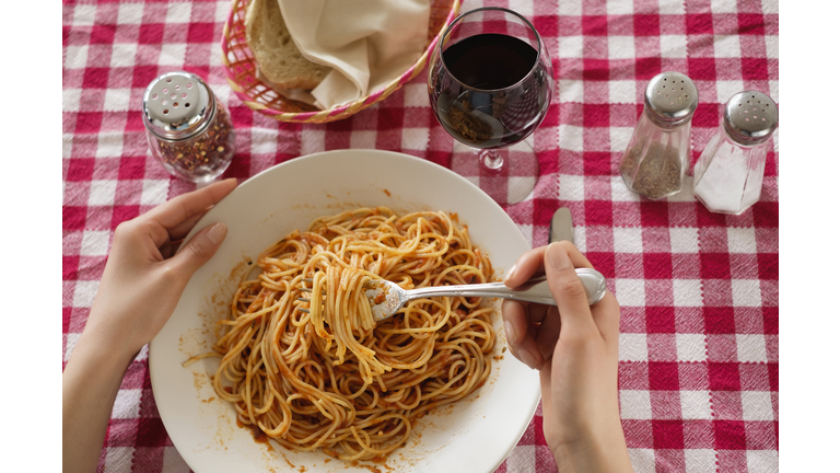 Hispanic woman eating plate of pasta