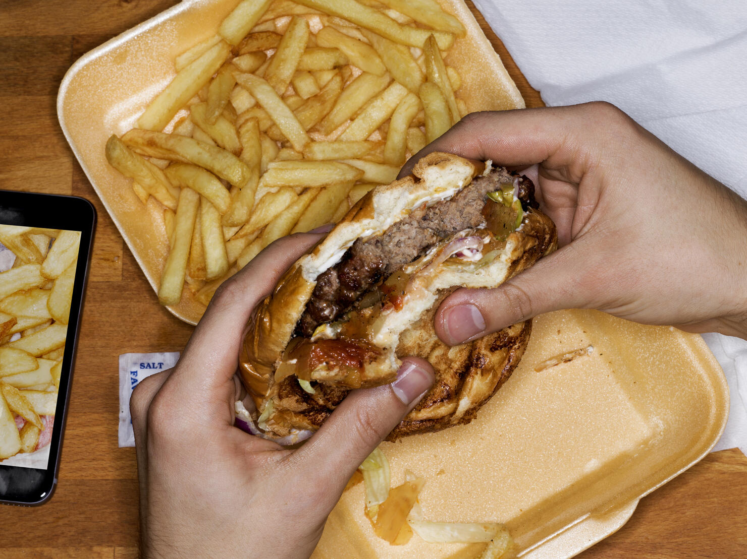 Men eating hamburger and fries, phone with picture