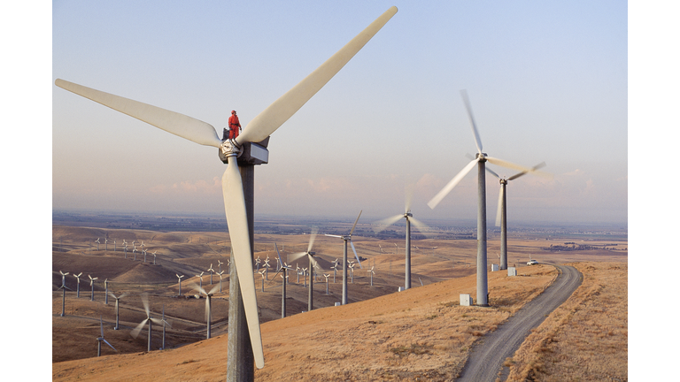 Worker standing on wind turbine at wind farm