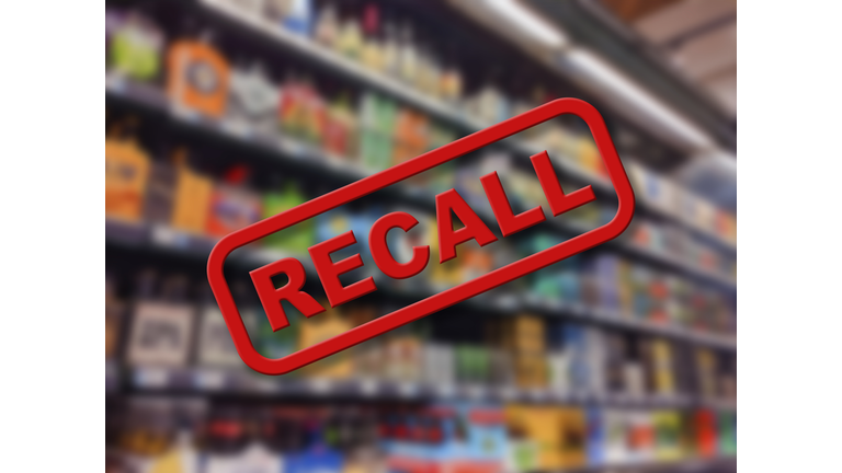 Blurry interior of a grocery store aisle behind large red Recall text