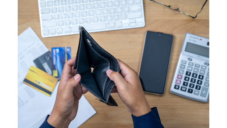 Close up man hand opening empty wallet over calculator.