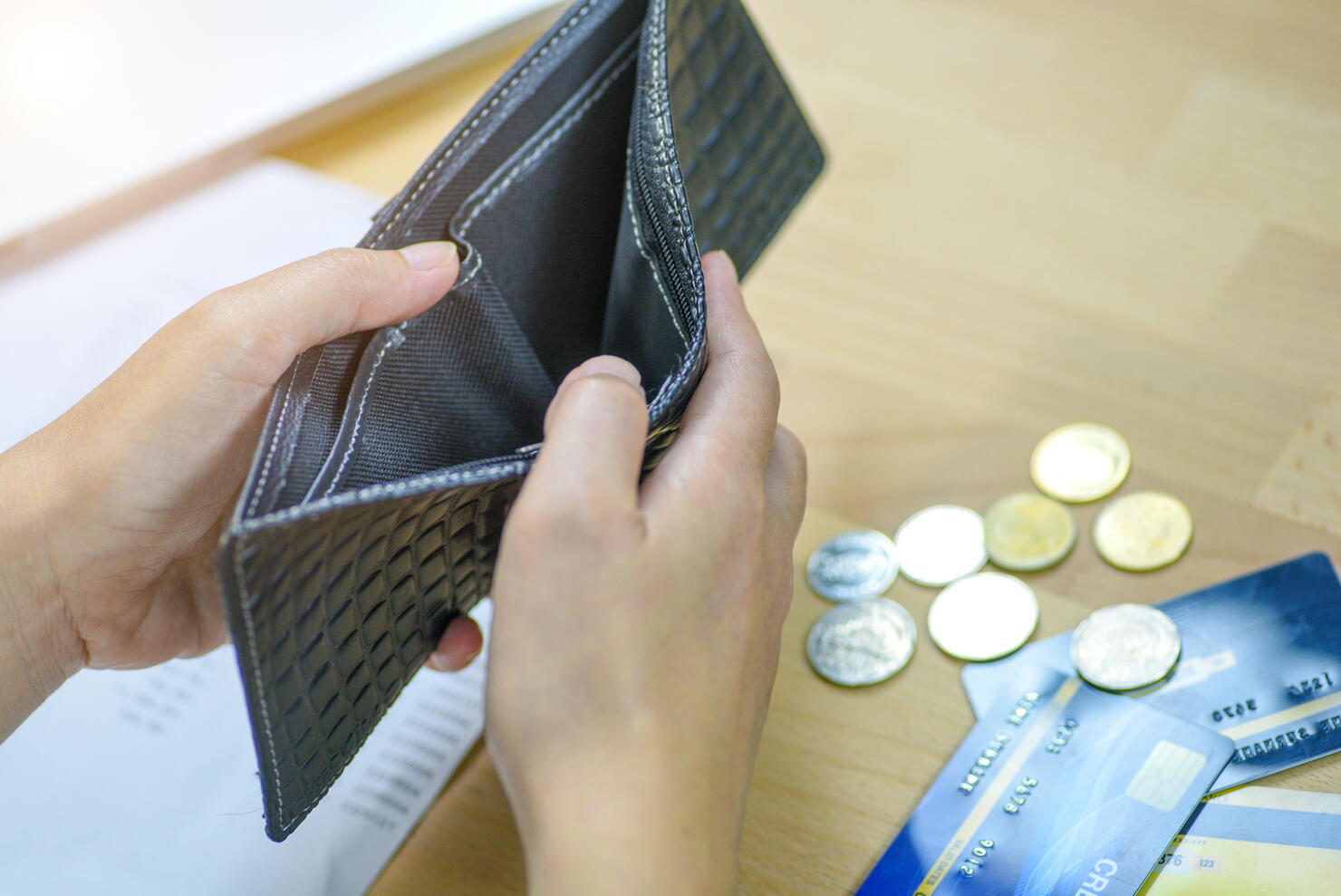 Man holding an empty wallet and few coins.