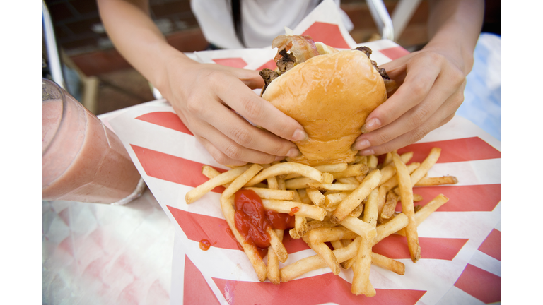 Hands of woman holding hamburger, close-up