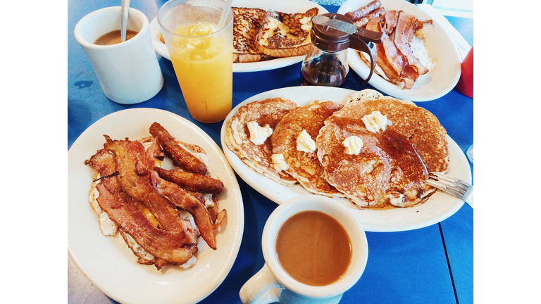 Classic American breakfast with fried eggs, bacon, pancakes, maple syrup and coffee served in a diner