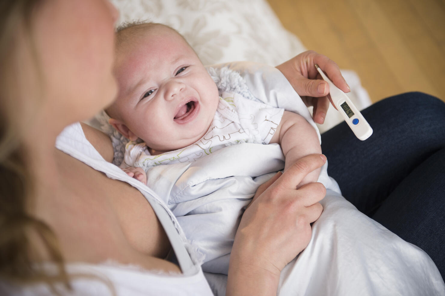 Caucasian mother taking crying baby's temperature