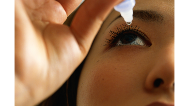Woman using eye drops, close-up