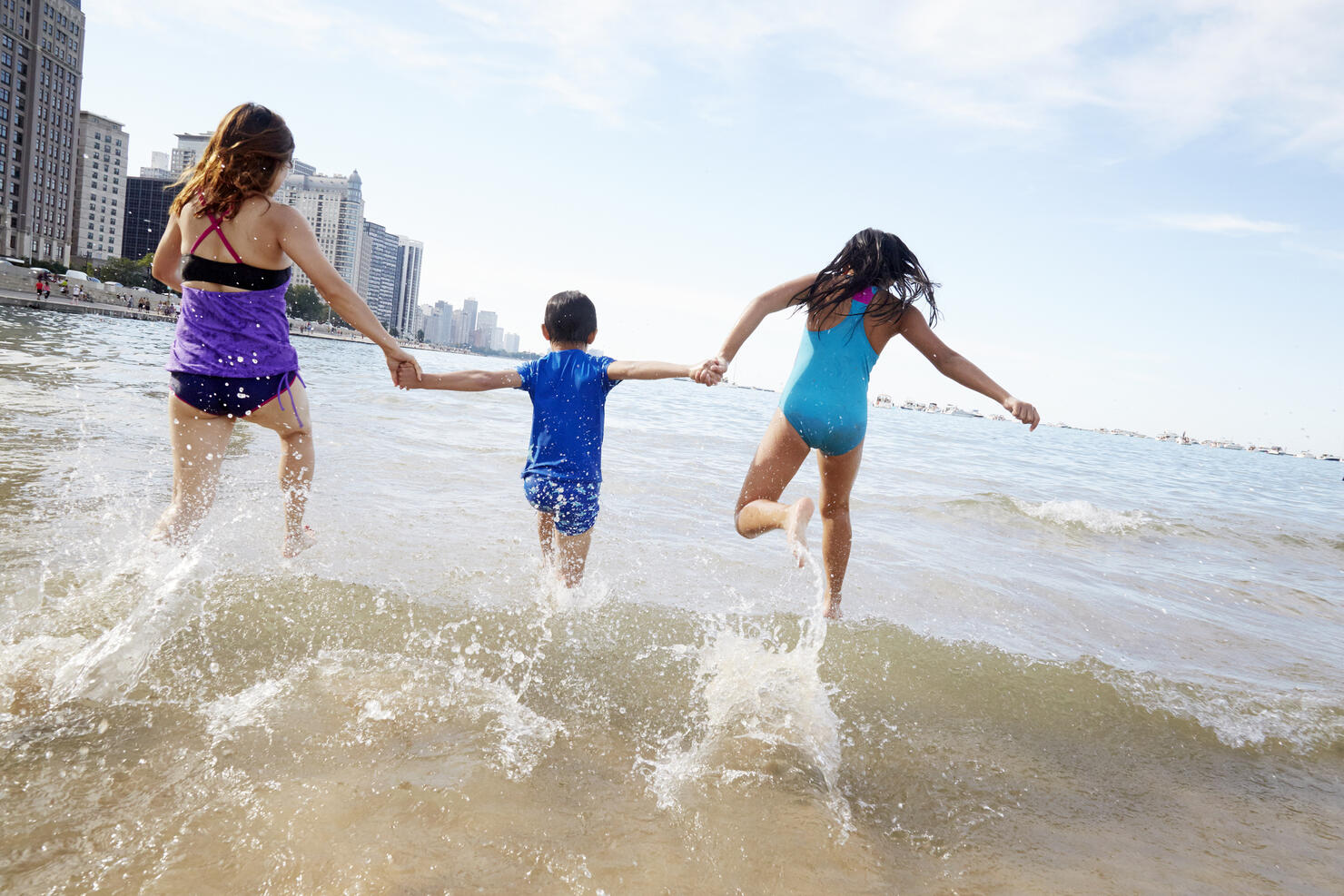 Family hand in hand running into the water