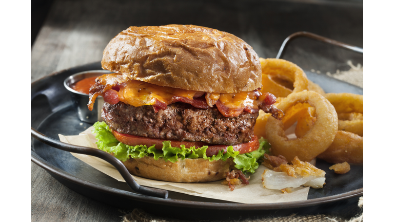 Bacon and Cheddar Burger with Lettuce, Tomato and Thick Cut Onion Rings on a Toasted Onion Bun