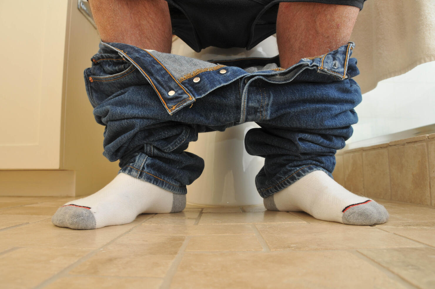 Man with pants down sitting on the toilet