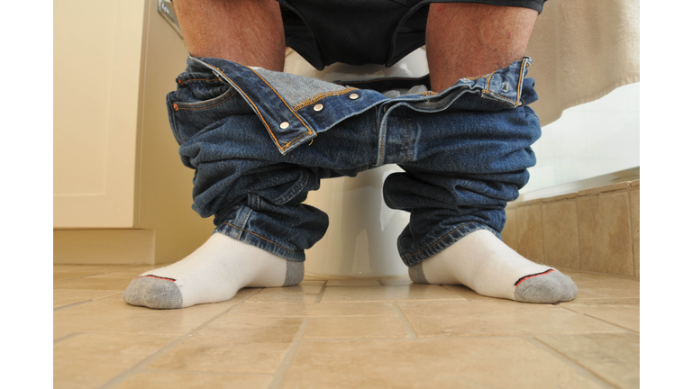 Man with pants down sitting on the toilet