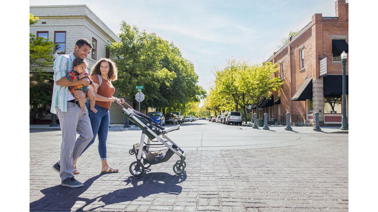 Young family strolling with baby daughter on city street