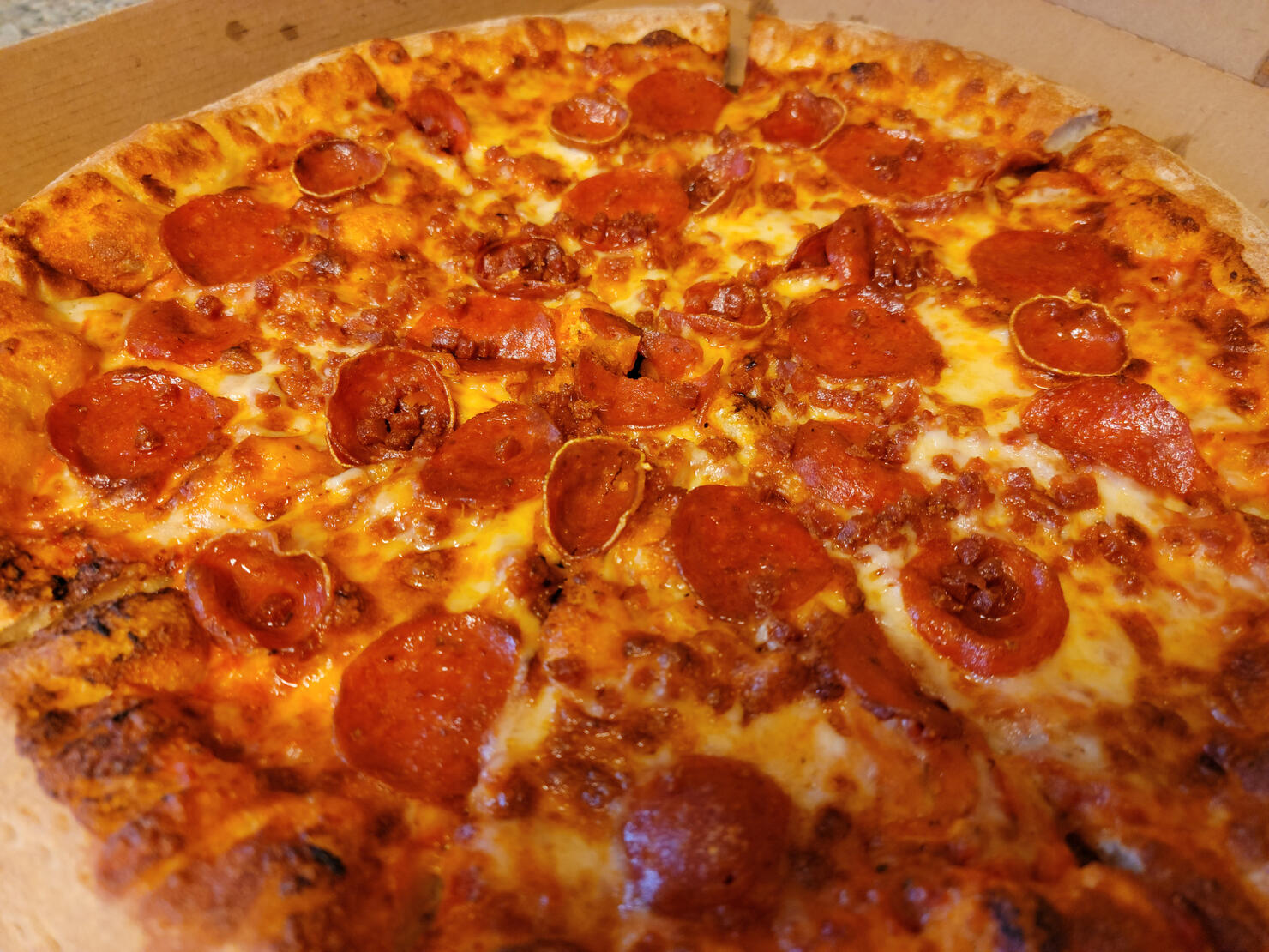 greasy pepperoni meat sliced pizza in cardboard box
