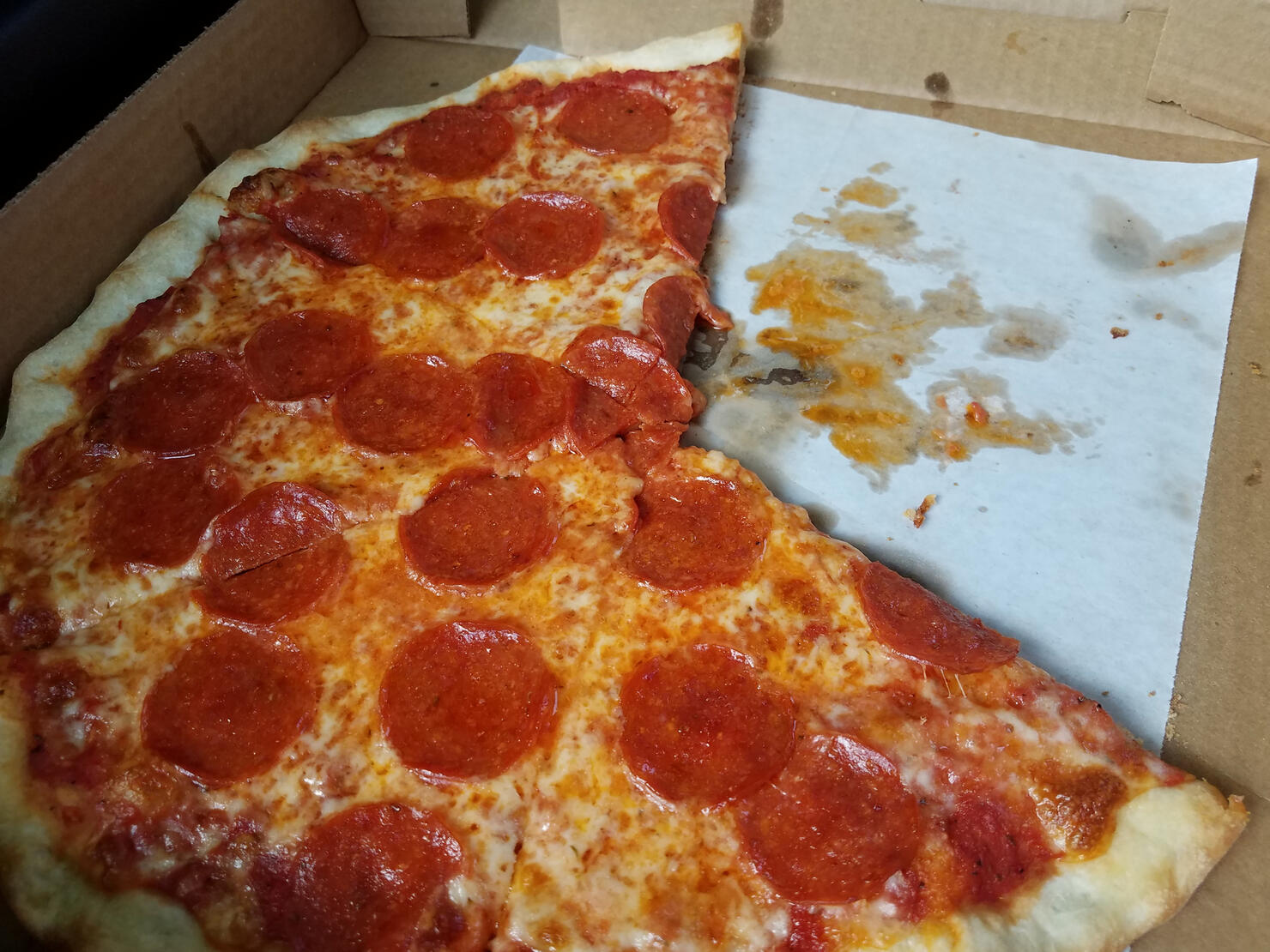 greasy pepperoni and cheese pizza in cardboard box