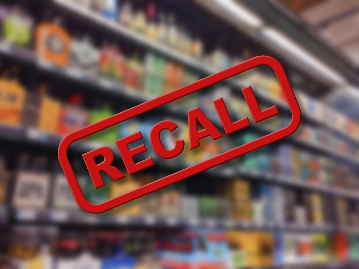 Blurry interior of a grocery store aisle behind large red Recall text