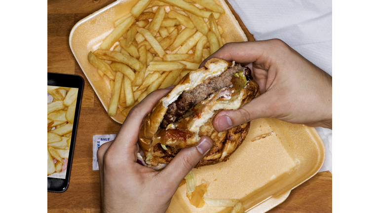 Men eating hamburger and fries, phone with picture