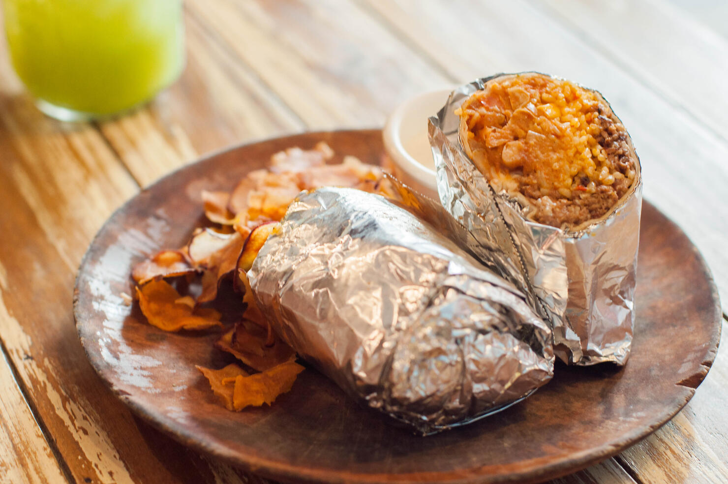 A close-up view of Mexican Burrito with sweet potato chips on a wooden table