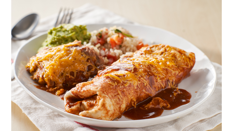 mexican wet burrtio platter with red enchilada sauce, refried beans, rice and guacamole