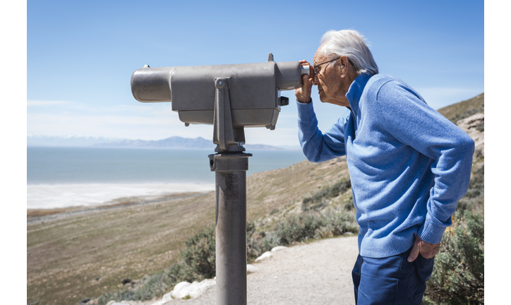 Senior man looking at scenic view with telescope