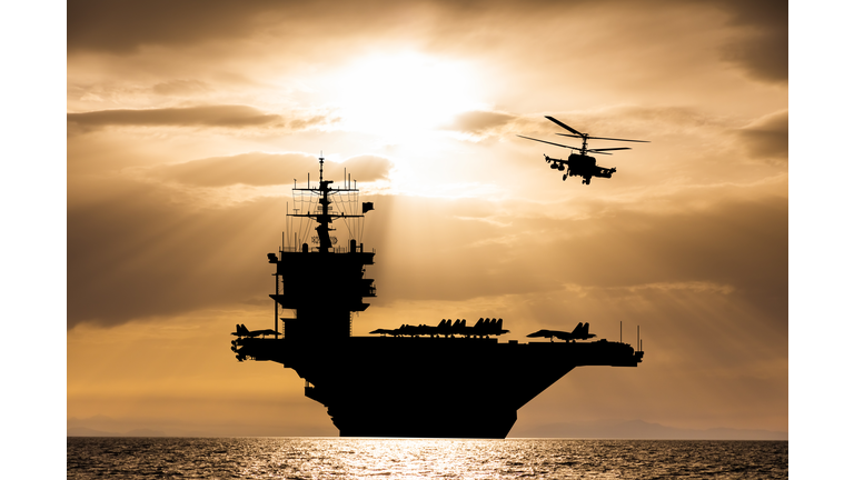 Aircraft carrier at sunset in the sea