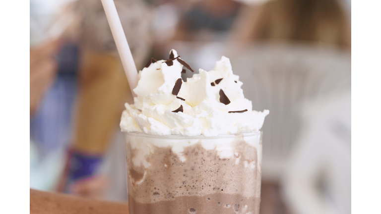 close-up of a woman's lips drinking from a frappuccino in a restaurant, side view