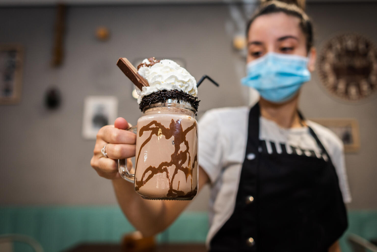 Waitress wearing face mask offering a chocolate milkshake