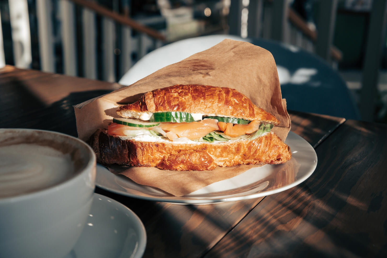 Fresh croissant with salmon slices, fresh cucumber and a cup of coffee for breakfast.