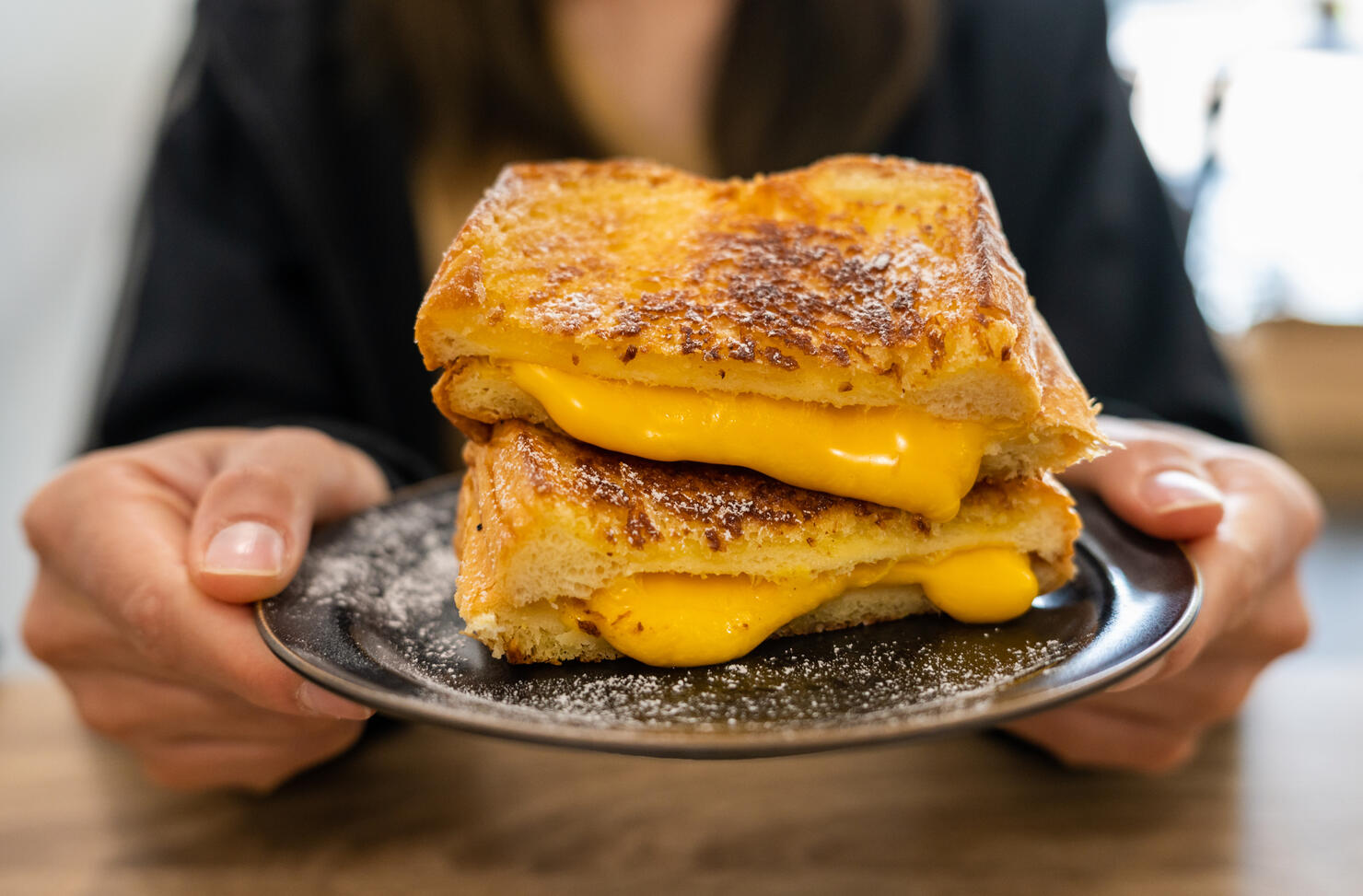 Someone holding a Cheese Toast before eating.