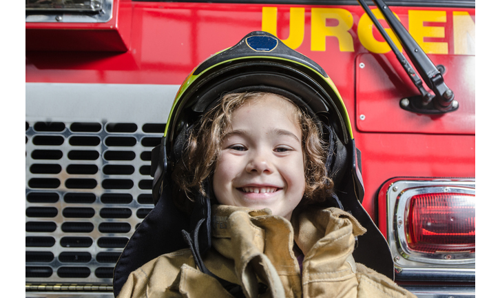 Young girl wearing fireman coat and helmet