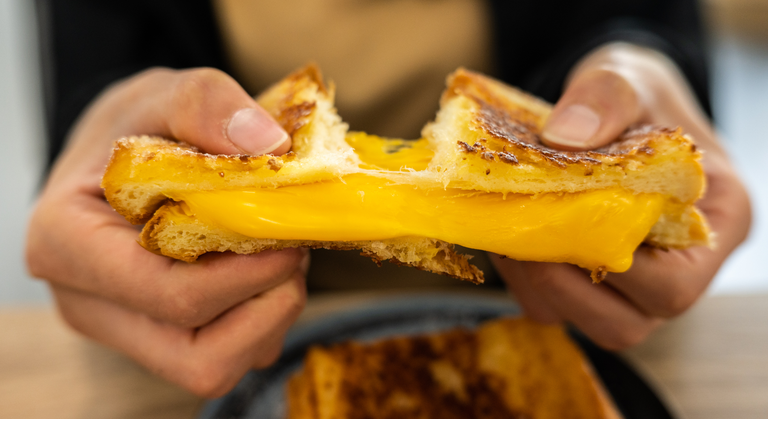 Someone tearing a Cheese Toast before eating.