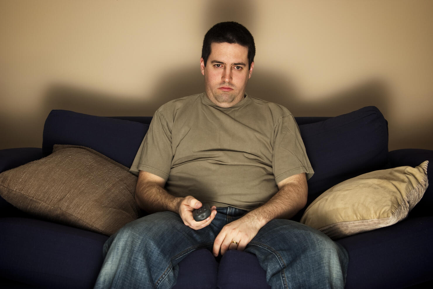 Bored, lazy, overweight man sits on the sofa